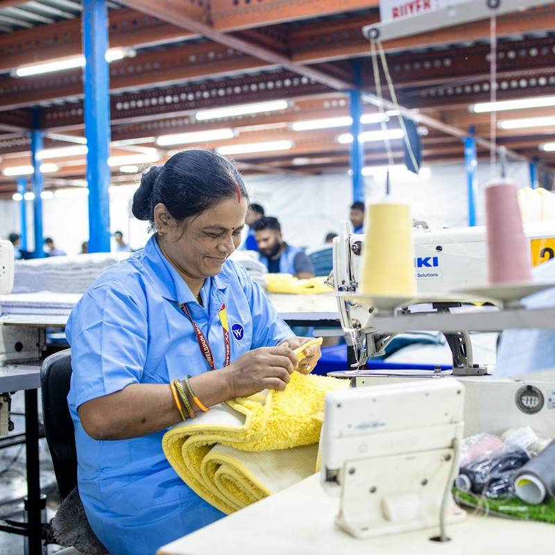 A machinist stitching yellow fabric on an industrial sewing machine