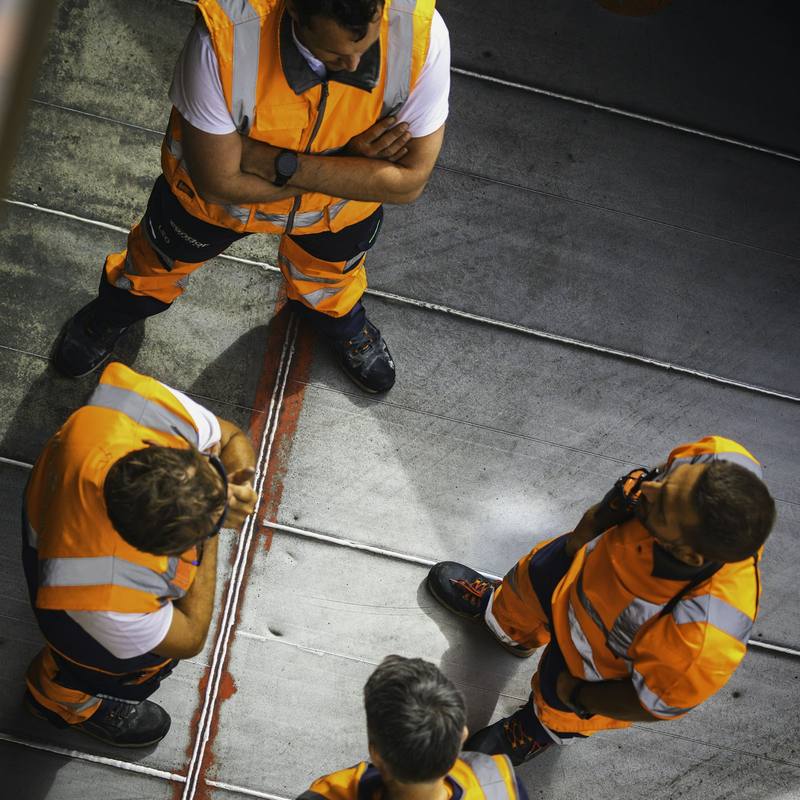 Workers in orange high-visibility workwear seen from above